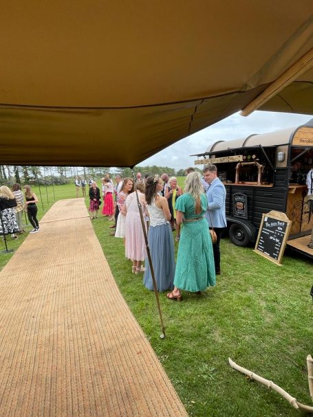 A group of people in colourful dresses gathered near a food truck at an outdoor event.
