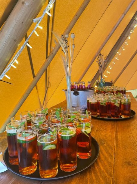 A tray of glasses with iced tea garnished with lime, set under warm lighting.